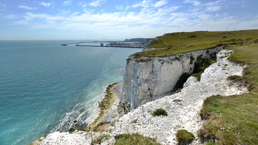 View from the clifftop at The White Cliffs of Dover, Kent with blue sky, light clouds and the port of Dover in the background